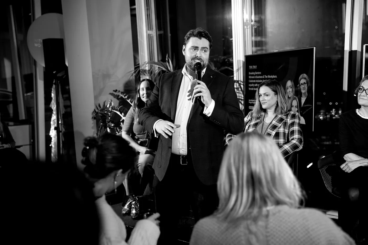 Rhys Morris hosting an evening event with panellists seated behind him